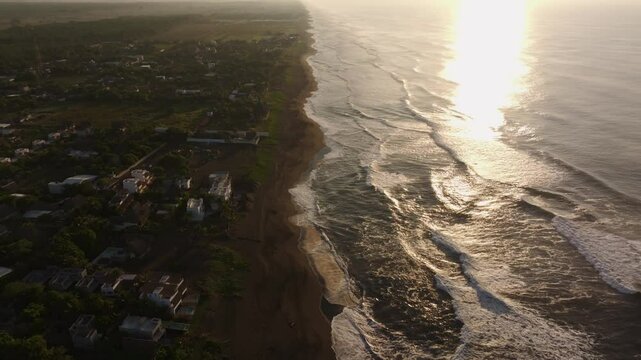 Aerial view of sandy beach with waves under morning sunlight, El Paredon, Guatemala.