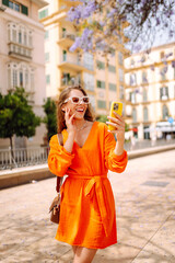 Fototapeta premium Happy young travel woman using mobile phone and relax on street market. Travel, tourism, technology, blogging, communication concept.