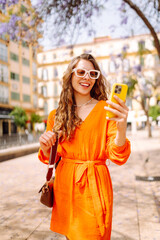 Happy young travel woman using mobile phone and relax on street market. Travel, tourism, technology, blogging, communication concept.