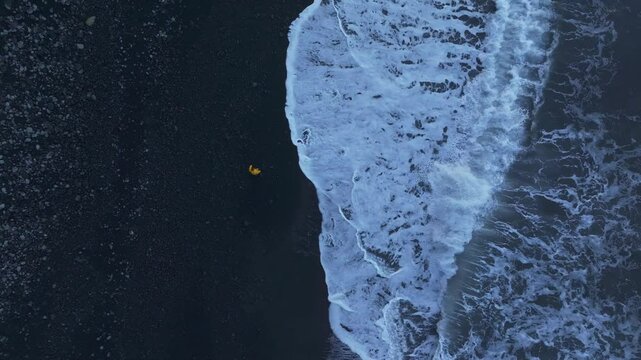 Aerial view of man walking on black sand beach at sunrise, Lajes das Flores, Azores, Portugal.