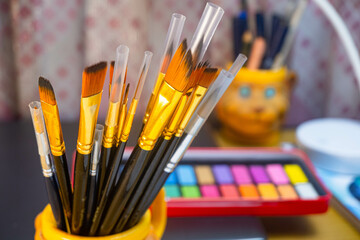 Artistic equipment. Painting brushes with a watercolor color palette background. Paint brushes, watercolor color palette on work table. A set of brushes