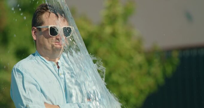 Middle-aged man getting unexpectedly doused with a bucket of water