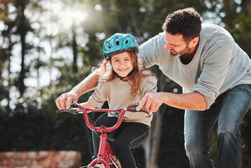 Dad, little girl and learning with ride on bicycle for teaching, lesson or practice at outdoor park. Happy father, daughter or child with smile on bike for bonding, training or cycling in nature