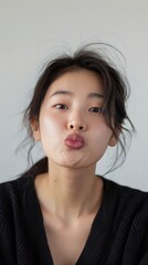 Fototapeta premium Korean woman blowing a kiss towards the camera whi 181 woman, child, beauty, face, hair, people, smiling, smile, eyes, person, model, kid, youth, one, brunette, fashion, studio, fun, baby, teenager, 