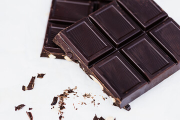 Detail of two chocolate bar pieces with broken bits on white background, copy space.