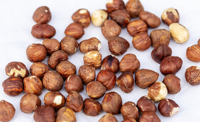 Collection of hazelnuts spread out on white background.