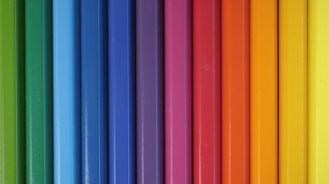 Colored pencils stacked in a row are illuminated by a spotlight from left to right. Close up