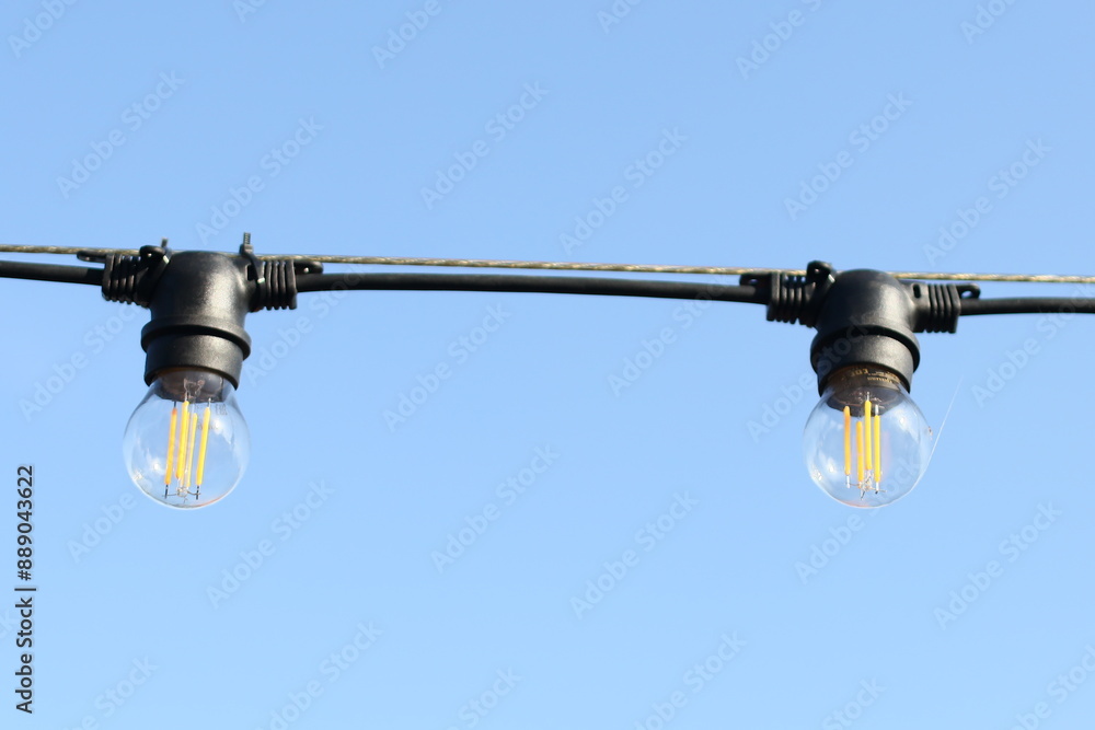 Poster a pair of lights mounted on a wire, suitable for use in various settings such as outdoor events or i