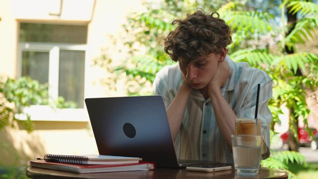 Portrait of stressed teenage boy stressed overwhelmed by homework studying outdoors near campus alone 