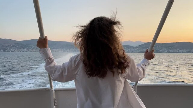 Happy woman looks out of hatch of yacht cabin enjoying relaxation and breathtaking view of nature. young girl rides on yacht, motor boat, hair is blown by wind. Traveling on a yacht
