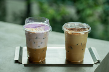 Close up glass of ice coffee with taro milk and ice cappucino  on raw cement table of a coffee shop summer terrace, menu photography.