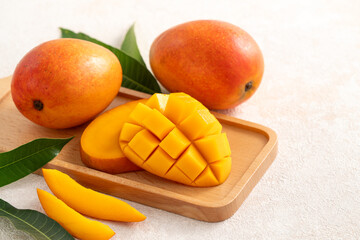 Fresh slice cut juicy mango on gray table background with leaf.