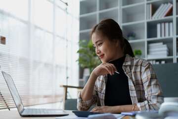 woman meticulously plans a finance audit, using a computer and calculator to review budget documents and ensure accuracy