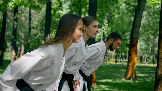 outdoors in the park in sunny weather young karatekas are warming up using the karate technique martial arts black belt healthy lifestyle combat training