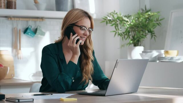 Video of tressed business woman working from home on laptop looking worried, tired and overwhelmed int he kitchen at home.