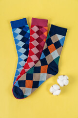 Three pair of colored socks with rhombuses on yellow background. advertising, branding, Mock up,...