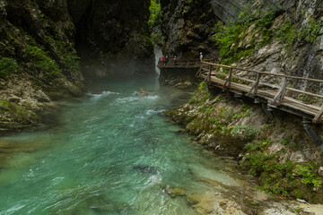 Vintgar Gorges Park a few km from Lake Bled, Slovenia. Wooden walkways accompany the path above the river rapids and waterfalls. River hits rocks and creates fog.Adventure family holidays. Freshness.