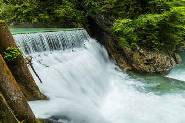 Obraz premium Vintgar Gorges Park a few km from Lake Bled, Slovenia. Wooden walkways accompany the path above the river rapids and waterfalls. River hits rocks and creates fog.Adventure family holidays. Freshness.