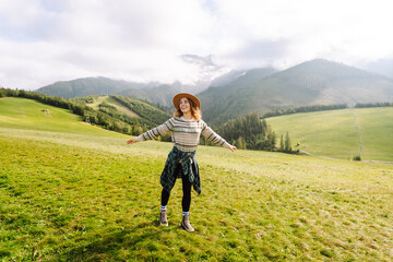 Fototapeta premium Happy woman walking green grass field, admiring landscape. Adventure and travel exploring