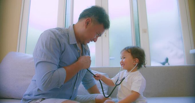 cute small child and father game as Doctor holding Stethoscope listening to father patient pretending nurse having fun with dad in cozy living room at home, capturing a heartwarming family moment.