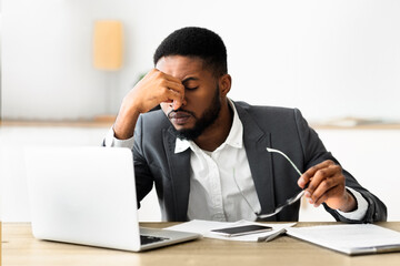 Naklejka premium Overworked african american employee taking off glasses after hard day in office, copy space
