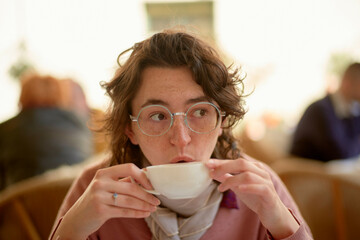 Woman enjoying a hot drink in a cozy caf� setting