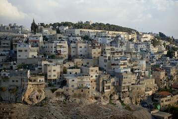 A panoramic view of densely packed residential buildings on a hillside under a clear sky at dusk.
