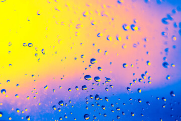 Window with raindrops on it. The raindrops are scattered all over the window, creating a blurry and hazy effect. Scene is calm and peaceful, as the raindrops seem to be falling gently