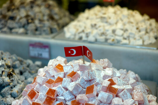 Turkish delight displayed in large quantities with a flag of Turkey atop the confectionery at a marketplace.