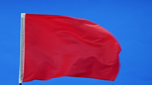 Slow motion video of red flag waving on blue background