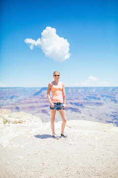 Woman standing in front of the Grand Canyon with a cloud above her head resembling thought bubble