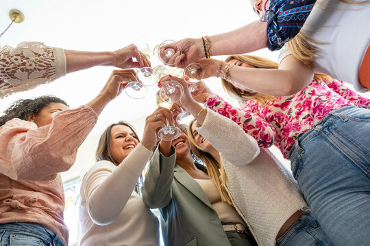 Group of friends toasting with champagne at a celebration, captured from a low angle.