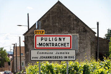 Obraz premium Road sign Puligny-Montrachet village, wine of Burgundy, France. High quality white dry wine making from Chardonnay grapes on grand cru classe vineyards