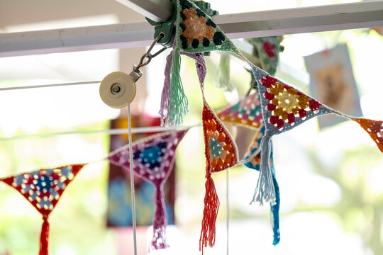 Colorful crochet bunting flags decorated with sequins hanging outdoors.