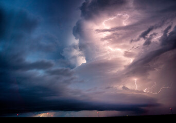 Lightning forks illuminate the night sky amidst swirling storm clouds.