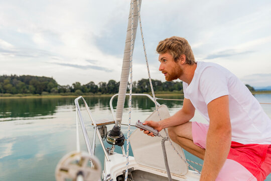 Man steering a boat with focus and attention on a calm lake during a serene day.
