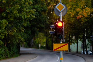 traffic semaphore with red light on defocused background of autumn city, closeup