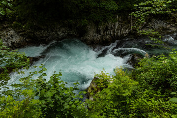 Vintgar Gorges Park a few km from Lake Bled, Slovenia. Wooden walkways accompany the path above the river rapids and waterfalls. River hits rocks and creates fog.Adventure family holidays. Freshness.