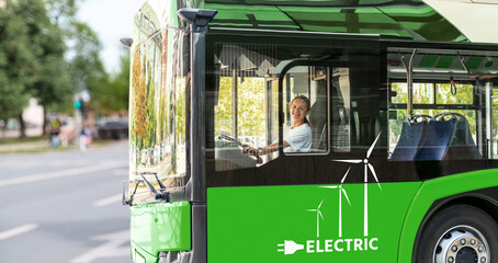 Young adult female person drives a green electric bus in city.