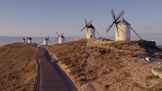 Aerial view of traditional windmills and castle with scenic sunrise, Consuegra, Spain.