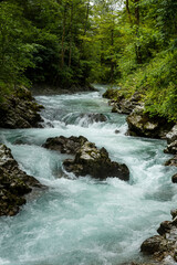 Obraz premium Vintgar Gorges Park a few km from Lake Bled, Slovenia. Wooden walkways accompany the path above the river rapids and waterfalls. River hits rocks and creates fog.Adventure family holidays. Freshness.