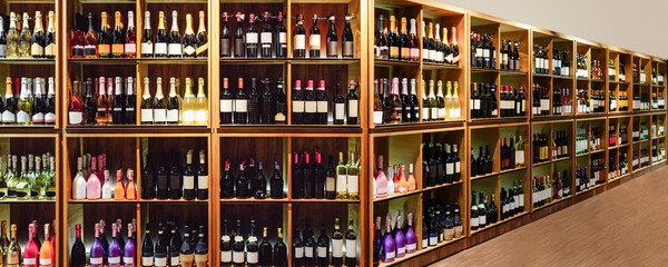 Wine store with wooden shelves full of bottles of wine and champagne.