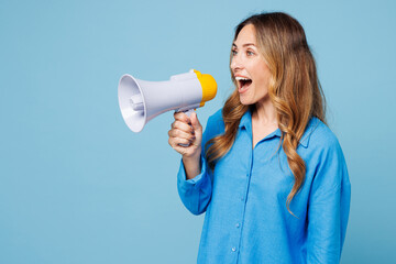 Young shocked woman wear shirt casual clothes hold in hand megaphone scream announces discounts sale Hurry up isolated on plain pastel light blue cyan background studio portrait. Lifestyle concept.