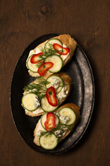 Сheese and cucumber baguette canapes, rustic still life top view