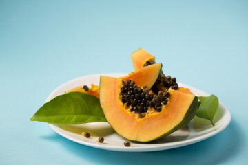 Juicy papaya in a white plate on a blue background