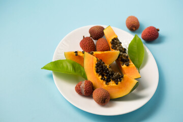 Ripe papaya and lychee on a blue background