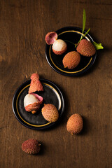 Tropical lychee berries on a black plates on a wooden background