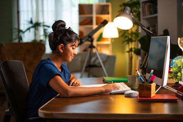 Asian Indian school girl studying at home on computer