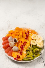 A large plate with sliced ​​various fruits on a light background