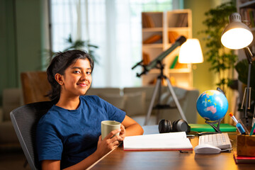 Asian Indian small girl takes break from study drink milk in cup